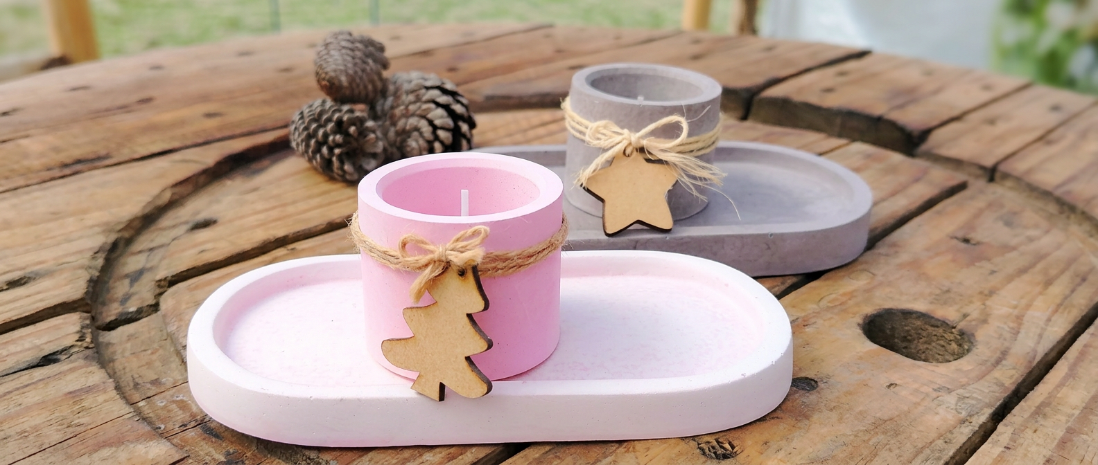Colección de piezas de cemento blanco teñido en tonos pastel — rosa, durazno, menta, lavanda y blanco — alineadas sobre mesa de madera